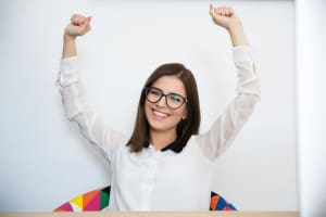 Happy young businesswoman with arms raised up