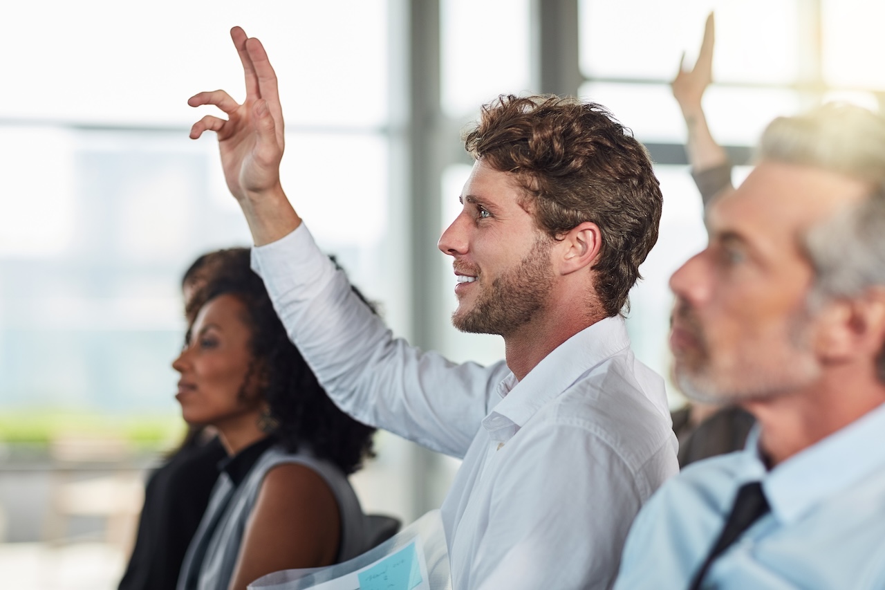 Cropped shot of a handsome young businessman raising his hand during a seminar.